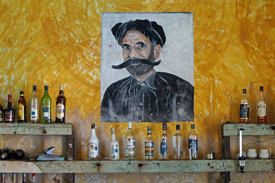 Sculpture of bottles on shelf against wall