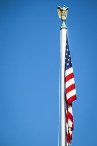 Low angle view of flag against clear blue sky