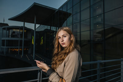 Portrait of woman standing against building