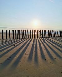 Wooden posts on beach against sky during sunset