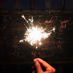 Close-up of hand holding sparkler at night