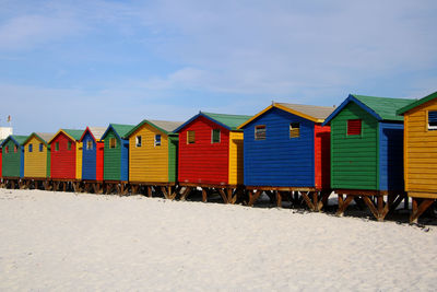 Multi colored huts at beach against sky