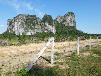 Fence on field by mountain against sky. cave looks like ancient cave. pahang. kuantan.