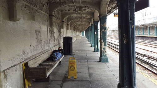 Full length of man sleeping on bench at railroad station platform