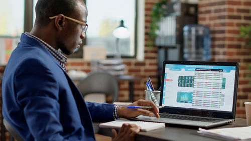 Rear view of man using laptop at office