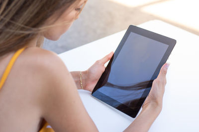 Teenage girl using digital tablet at sidewalk cafe in city