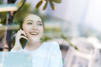 Portrait of smiling young woman using mobile phone outdoors