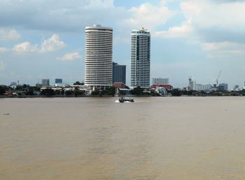 City buildings by sea against sky