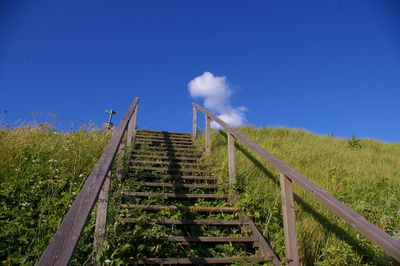 Staircase on landscape against blue sky