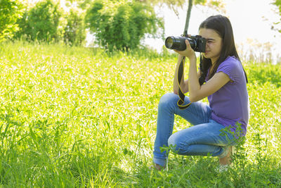 Side view of woman photographing on field