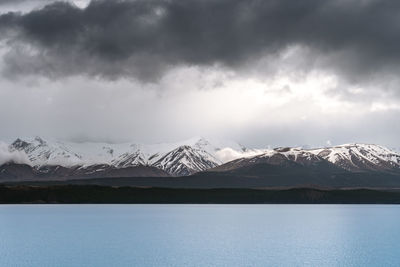 Gloomy landscape of new zealand southern alps and lake pukaki with blue sky and clouds.