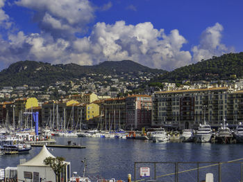 Sailboats moored in harbor against buildings in city