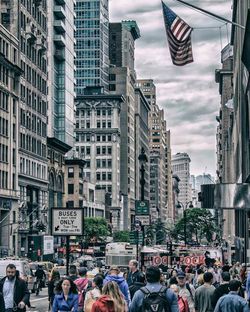 Crowd walking on city street against buildings