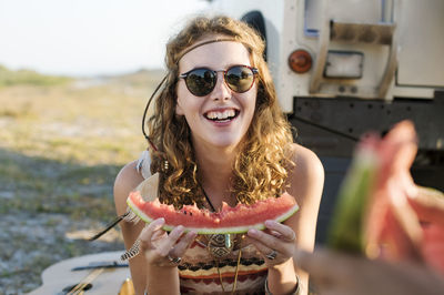 Happy woman eating watermelon at beach