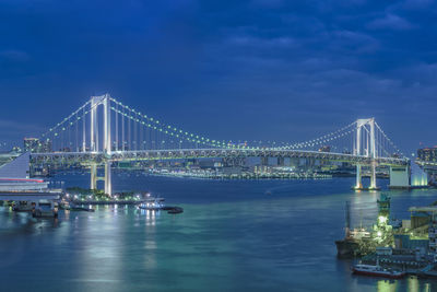 Illuminated rainbow bridge with cruise ships moored in odaiba bay of tokyo.