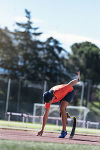 Athlete with prosthetic leg bending on sports track