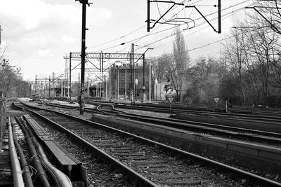 Power lines over railroad tracks against sky