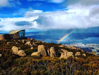 Scenic view of rainbow over rocks against sky