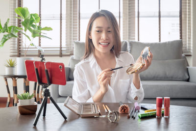 Young woman using phone while sitting on table