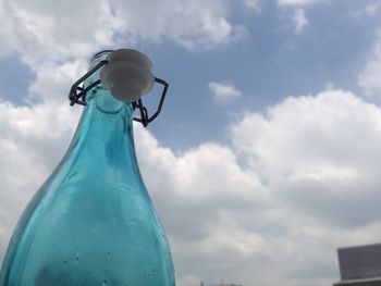 Low angle view of bottles against blue sky