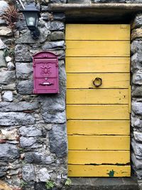 Yellow door and red mailbox on stonewall background