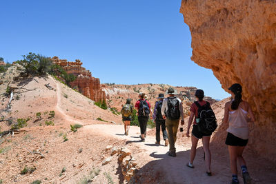 Rear view of people walking on mountain against clear blue sky