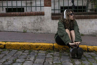 Portrait of young woman sitting on footpath