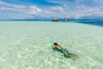 Man swimming in sea against sky