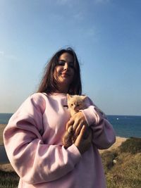 Woman with cat by sea against sky