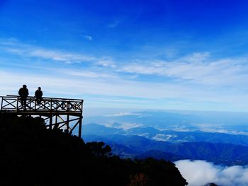 Silhouette people standing on mountain against cloudy sky