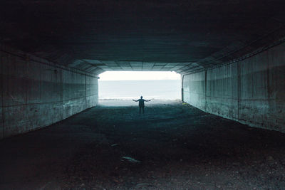 Rear view of man standing in tunnel against sea