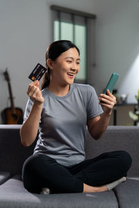 Young woman using mobile phone while sitting in gym