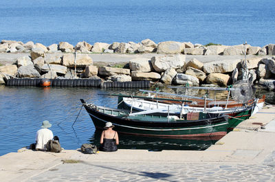 Rear view of people on boats moored at sea