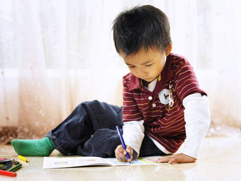 Boy coloring on book at home