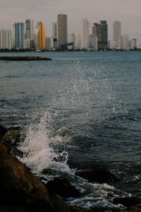 Sea by buildings against sky in city