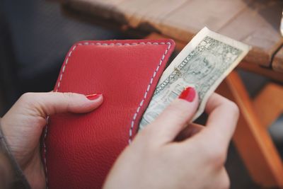 Close-up of woman removing paper currency from purse outdoors