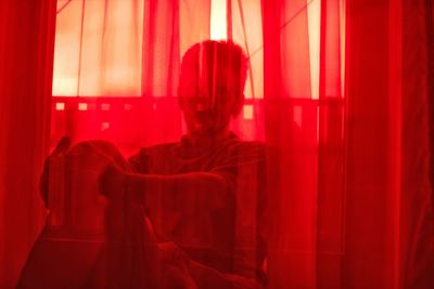 Man sitting behind red curtain
