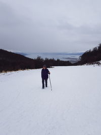 Full length of man on snow covered field against sky