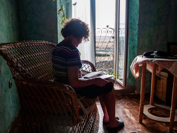 Woman reading book white sitting on seat at home