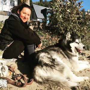 Full length of woman with dog sitting outdoors