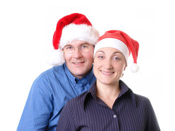 Portrait of smiling couple in santa hat against white background