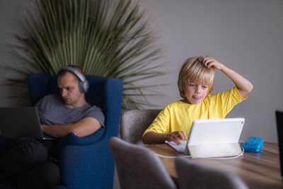 Rear view of woman using laptop while sitting on sofa at home