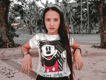 Portrait of teenage girl sitting against trees