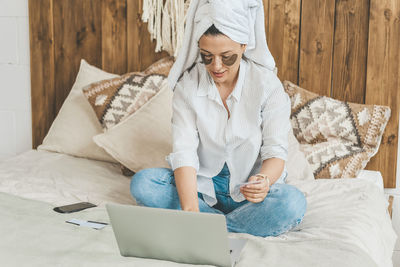 Woman at home on bed makes purchases on the internet. the joy of the black friday sale.