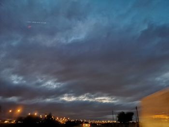 Low angle view of illuminated city buildings against dramatic sky