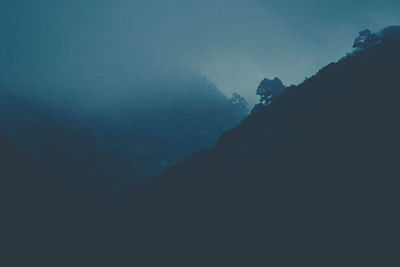 Low angle view of silhouette mountain against sky during winter