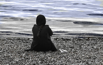 Rear view of woman sitting on beach