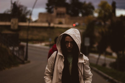 Woman wearing hood shirt standing on road