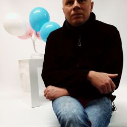 Midsection of man holding balloons against white background