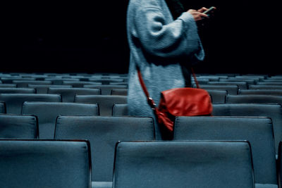 Midsection of woman using phone while standing in movie theater